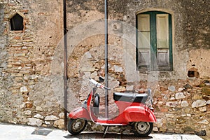 Red scooter by a rustic house