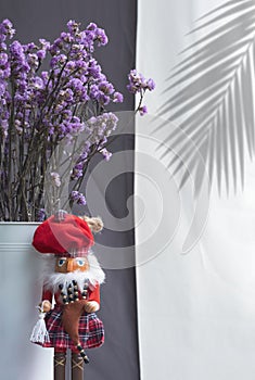 Red Scottish doll with dried purple statice flowers in white bucket on white and grey cloth background