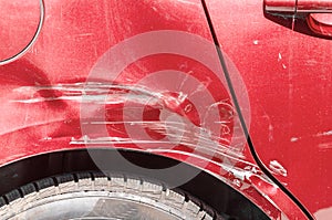 Red scratched car with damaged paint in crash accident on the street or collision on parking lot in the city