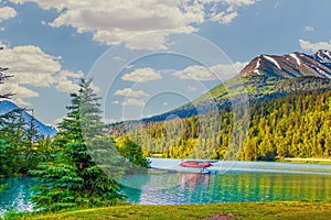 Red sea plane on lake in Moose Pass, Alaska in evening sunshine with mountains in background and surrounded by evergreen trees