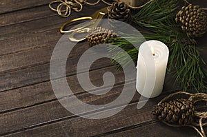 Red seasonal viburnum berries, white candle, fresh fir branches, cones and glass bottle of aromatic oils on the wooden table.Conce
