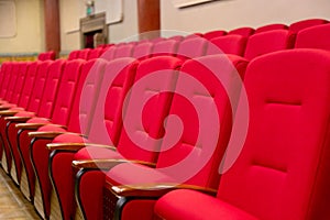 Red seats armchairs in theater in a row. Theater or conference room interior