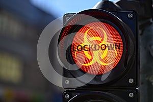 The red semaphore light with biohazard warning symbol and text LOCKDOWN, Covid-19  containment concept
