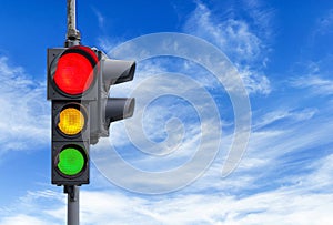 Red semaphore light with yellow and green and cloudy sky