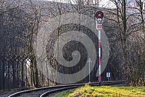 A red semaphore signal on a single-track railroad that turns rig