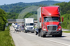 A red semi leads a line of traffic down an interstate highway in Tennessee