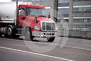 Red semi truck moving on highway and transporting fuel in tank