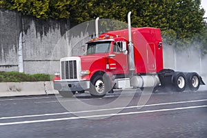 Red semi truck rig with long cab on raining highway