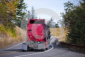 Red Semi trucks back convoy on winding fall road