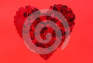 Red sequin in heart shape on red background. Valentine’s Day.