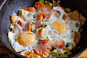 Red shakshuka. Fried eggs with tomatoes and onions, leek in a frying pan, close up