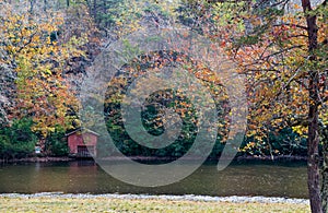 Red shed on bank of pond with autumn colors