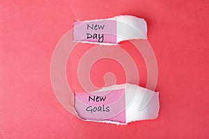 In a red sheet of paper, two holes are broken, in which there are inscriptions: `New day. New goals