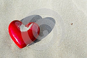 Red and shiny heart with some sand