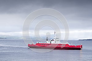 Red ship ferry transport over sea under dark storm clouds photo