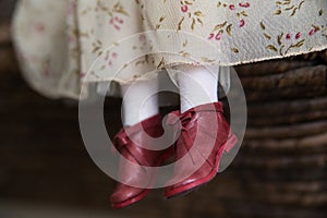 Red shoes on a doll`s leg in white tights
