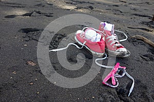 Red shoes and girls sunglasses on Waipio Valley black sand beach, Hawaii