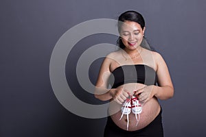 Red shoes for the unborn, maternity concept on grey background