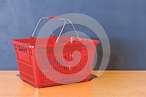 Red shopping basket on the wooden table. 3D rendering
