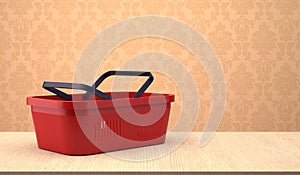 Red shopping basket on wooden table.