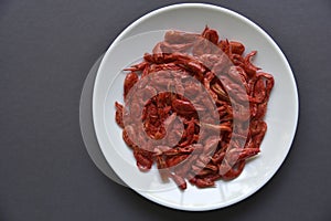 Red shrimp on a white plate and a matte black background. Delicious peppery appetizer on a platter. Fresh shrimp in the group