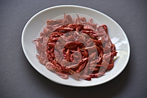 Red shrimp on a white plate and a matte black background. Delicious peppery appetizer on a platter. Fresh shrimp in the group