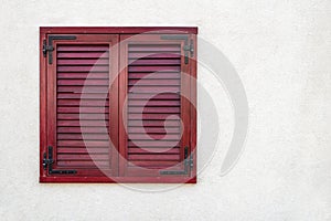 Red shuttered window on white stucco wall