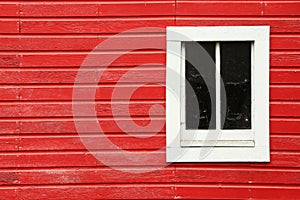 Red side of a barn with a bright, white window.