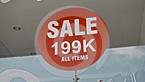 Red sign hanging on a glass window with the inscription Sale 199 K all items