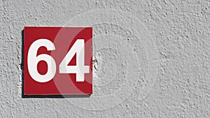 Red sign with number 64 on gray wall