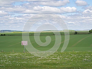 Red sign on open farmland stating out of bounds to unauthorised personnel indicating no public access or right of way
