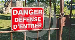 red sign placed on a rusty gate or it is written in French danger defended to enter
