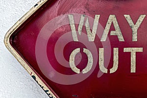 A red sign on a wall stenciled with the words Way Out
