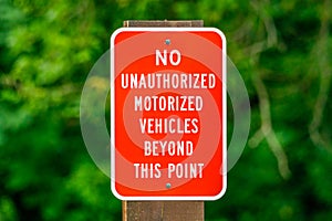 Red sign with white letters attached to a wooden post