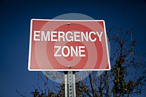 Red sign with white letters stating Emergency Zone