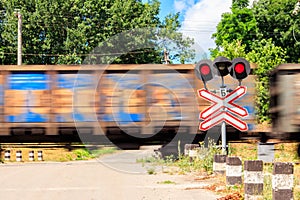 Red signal of semaphore and stop sign in front of railroad crossing with train passing