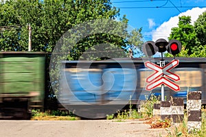 Red signal of semaphore and stop sign in front of railroad crossing with train passing