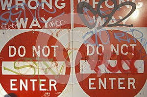 Red signs reading Ã¯Â¿Â½Wrong Way, Do Not EnterÃ¯Â¿Â½ covered with graffiti Los Angeles