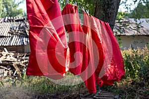 Red silk bedding, sheets, rope dry, hanging outside