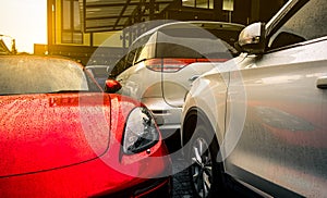 Red and silver car parked on outdoor concrete parking lot of the hotel, home, or apartment. Electric or hybrid car technology.