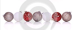 Red, silver and white Christmas balls in a row on a white