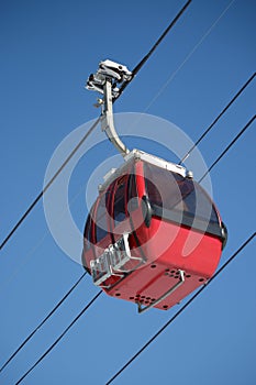Red ski gondola in clear blue sky overhead