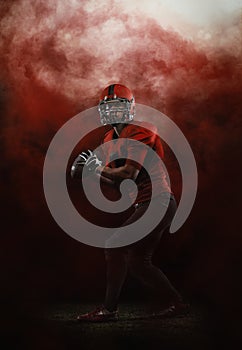 Red sky. Creative portrait of young man, american football player at stadium in motion on smoked background. Sport