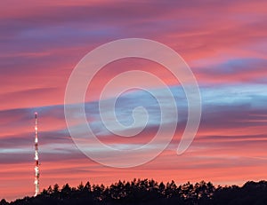 red sky sunset with trees silhouette and lighted transmitter