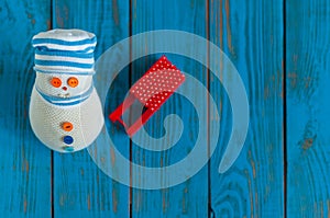 Red sled and handmade snowman on blue wooden