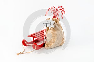 Red Sledge and Candy Canes in Jute Sack isolated on White