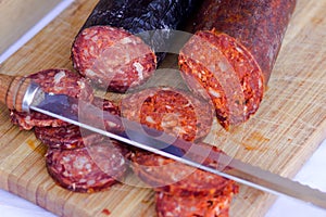 red sliced sausage on wooden board