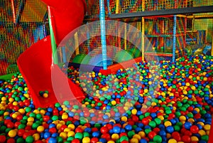 Red slide in big ball pool from playroom with colorfull net