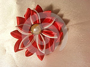 a red and slightly white lotus flower hand-crafted brooch decorated with a pearl bead in the center made of satin ribbon