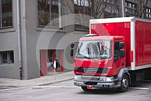 Red small box semi truck for delivery on city streets